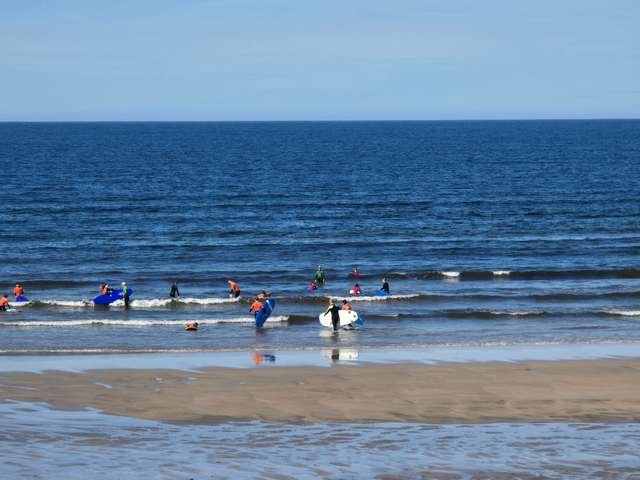 cutiny waves in front of the shop with a few beginners in the shallows